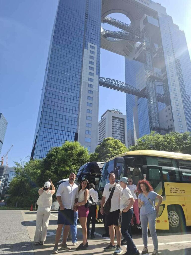 Private tour guests posing by the charter bus at the Umeda Sky Building.