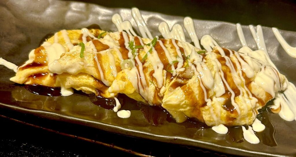 Tompeiyaki, an egg-wrapped pork dish drizzled with sauce and mayonnaise.