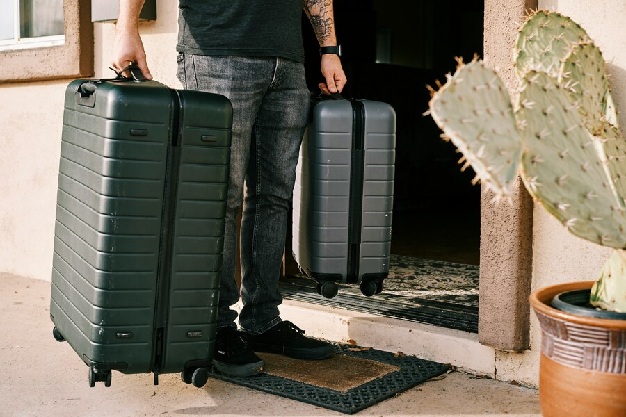 Traveler with luggage at a doorway.